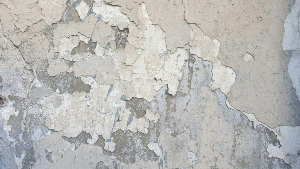 Pittura scrostata su parete con umidità