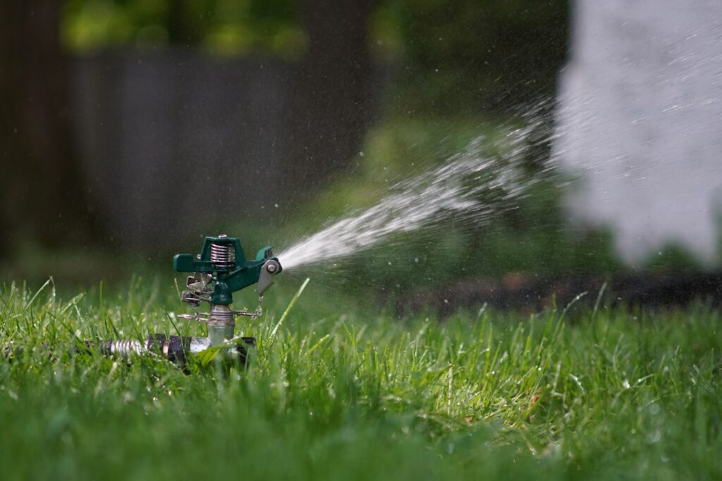Irrigatore da giardino con acqua sul prato vicino alla testina