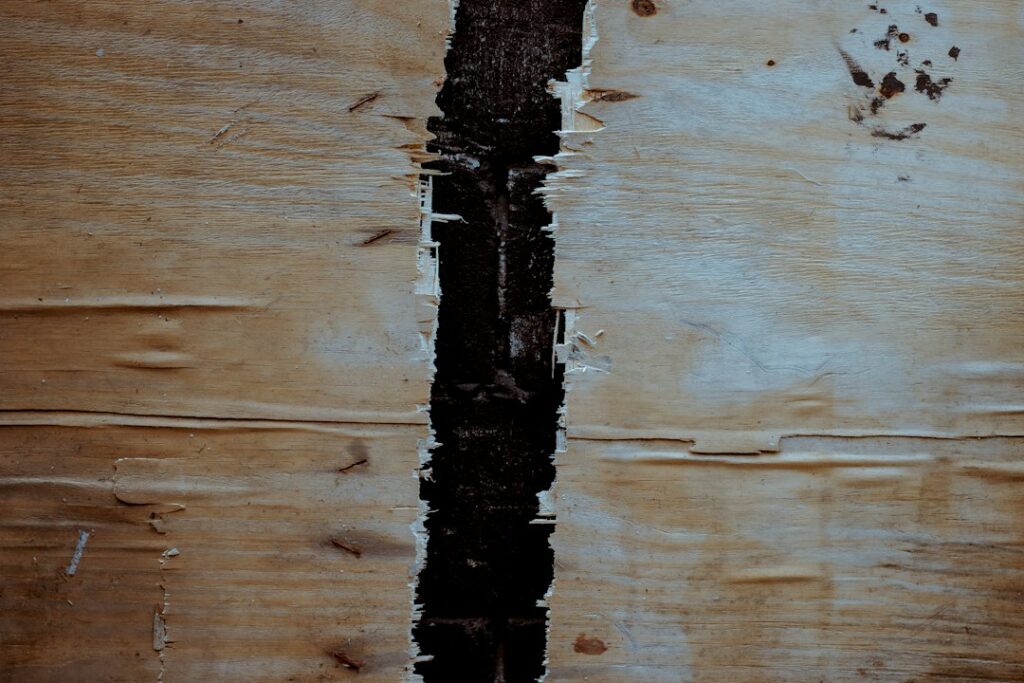Dettaglio di un pannello di legno gonfio e sfogliato dall’umidità