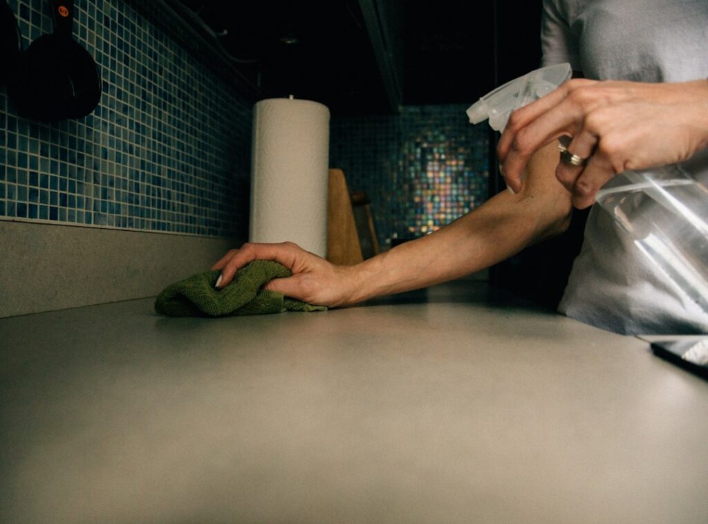 Mani con panno durante la pulizia delle superfici della cucina