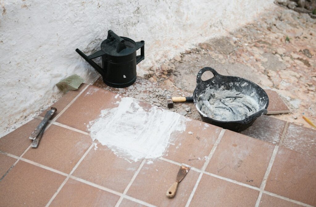 Attrezzi e materiali per la stuccatura delle fughe su un pavimento piastrellato