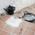 Attrezzi e materiali per la stuccatura delle fughe su un pavimento piastrellato