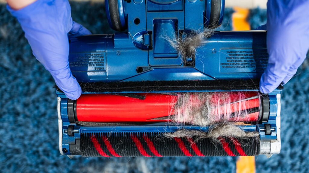 Rullo della spazzola dell’aspirapolvere ostruito da capelli e polvere
