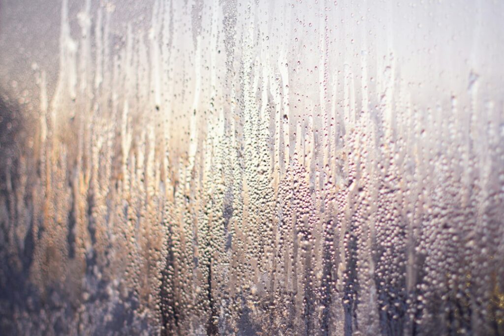 Condensa e umidità visibili sul vetro di una finestra durante il freddo
